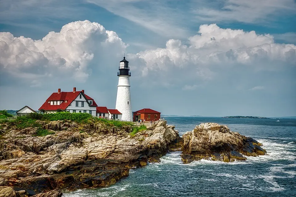 A white lighthouse on a rocky headland above the sea.