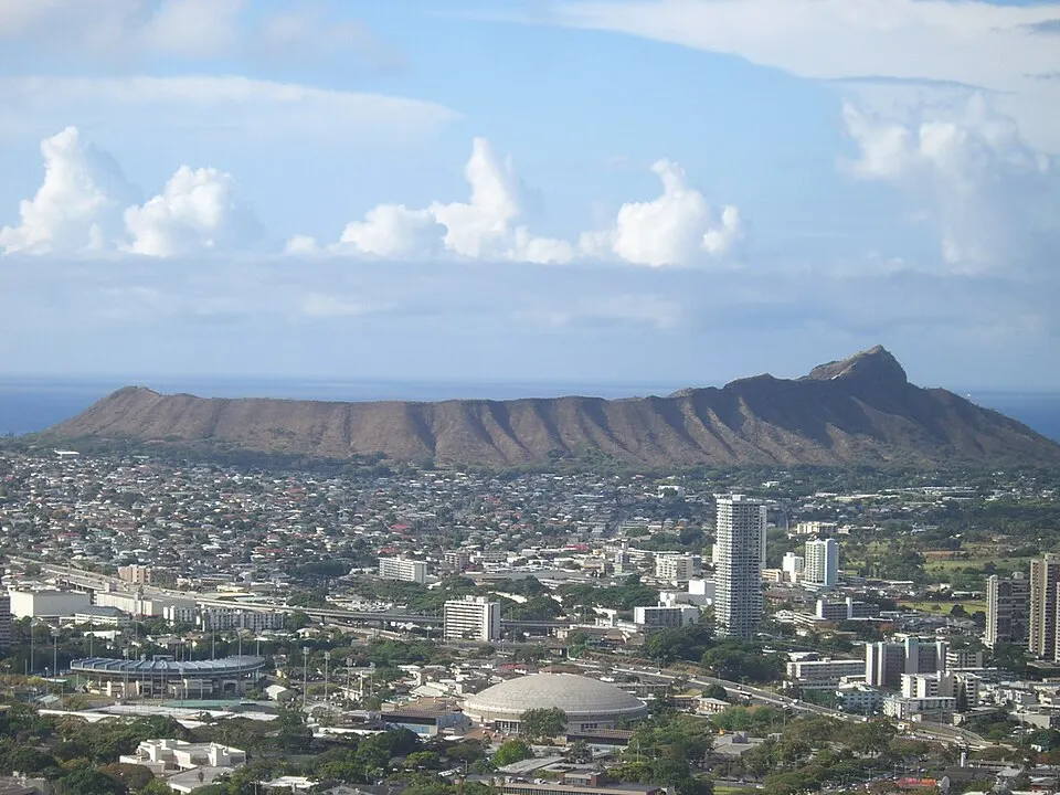 A volcanic crater ridge beside a curving beach and blue ocean.