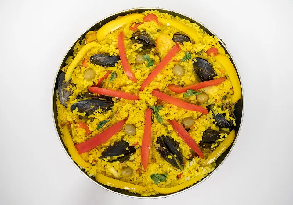 A wide shallow pan of saffron rice with meat and vegetables.