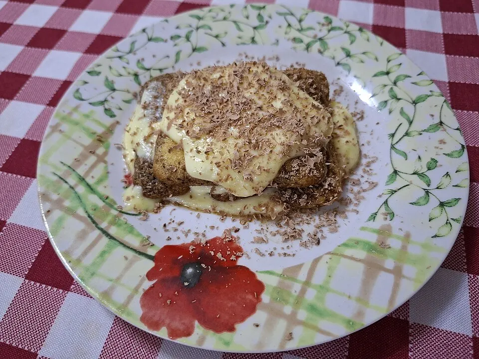 A square slice of layered cream dessert dusted with cocoa.