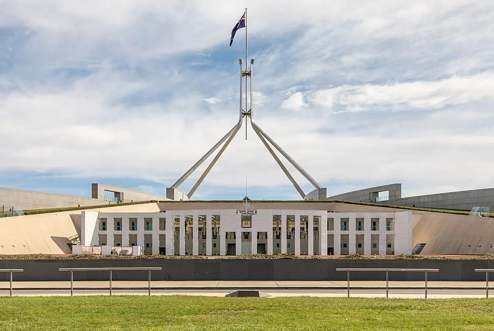 A low modern building with a giant flagpole on a green hill.