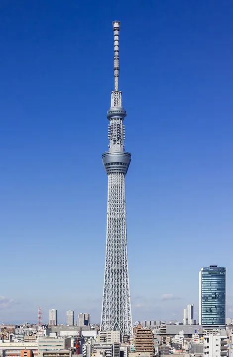 A very tall slender tower rising above a dense city.