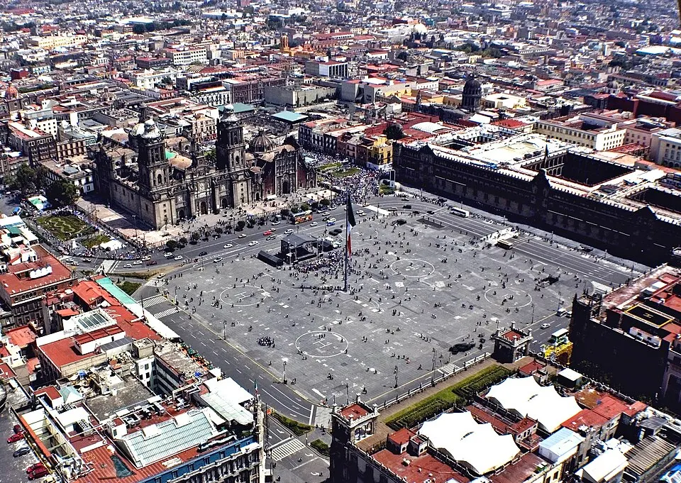 A vast city plaza with a huge flag and a cathedral beside it.