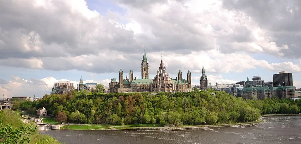 A gothic stone parliament building with a clock tower above a river.