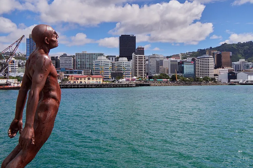 A bronze sculpture of a diver leaping above a harbour with a city skyline behind.