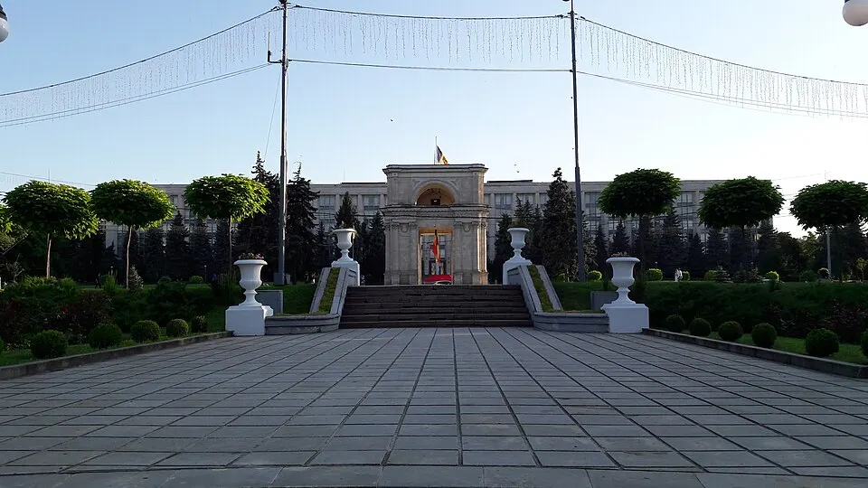 A stone triumphal arch in a city park with a wide avenue.