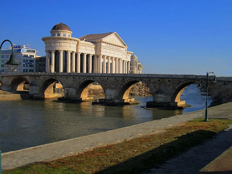 An old arched stone bridge over a river in a city centre.