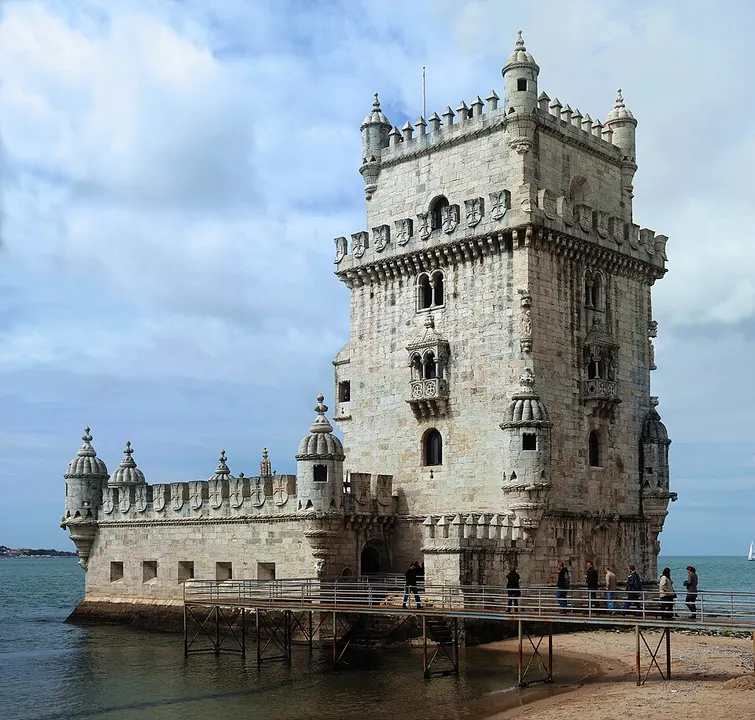A small ornate stone tower standing at the edge of a wide river.
