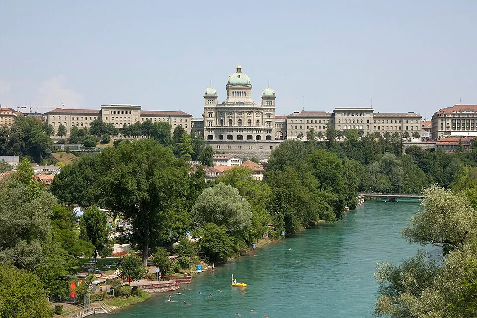 A stately domed stone building above a green river.