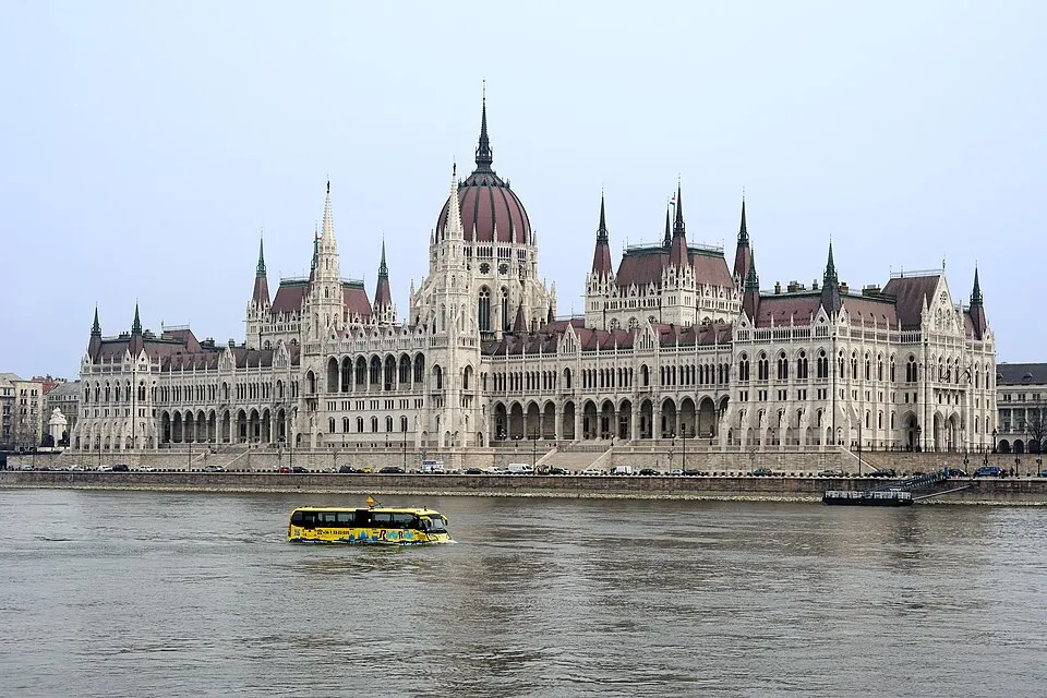 A huge neo-gothic parliament with a central dome on a riverbank.