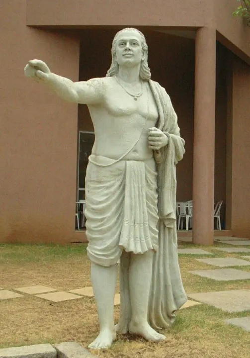 A statue of an ancient Indian scholar seated in meditation.