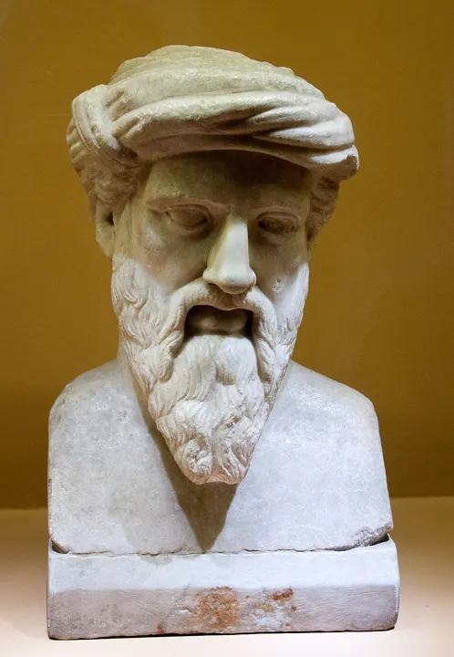 A marble bust of an ancient Greek man with a beard and headband.