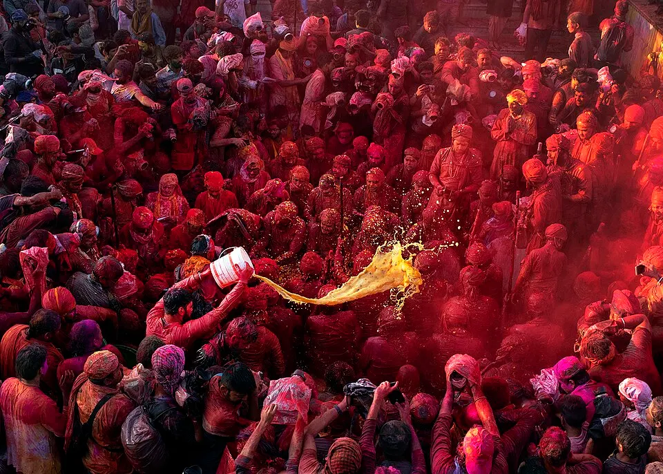 People smeared in bright powder colours, laughing in a crowd.