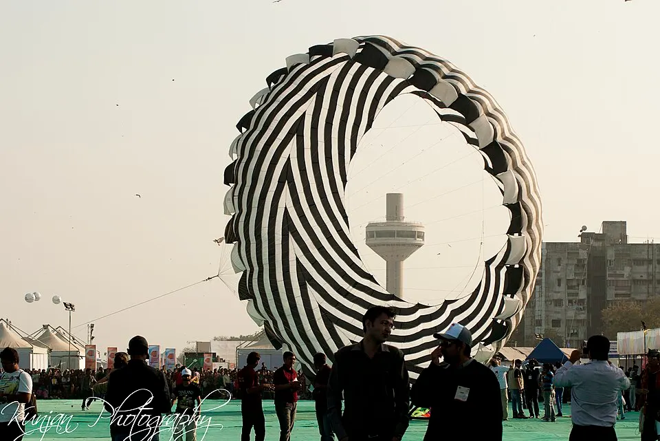A giant striped kite rising above a crowd at a kite festival.