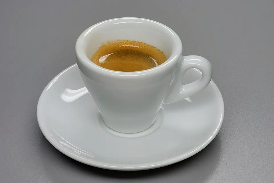 A tiny cup of espresso topped with a spot of milk foam.