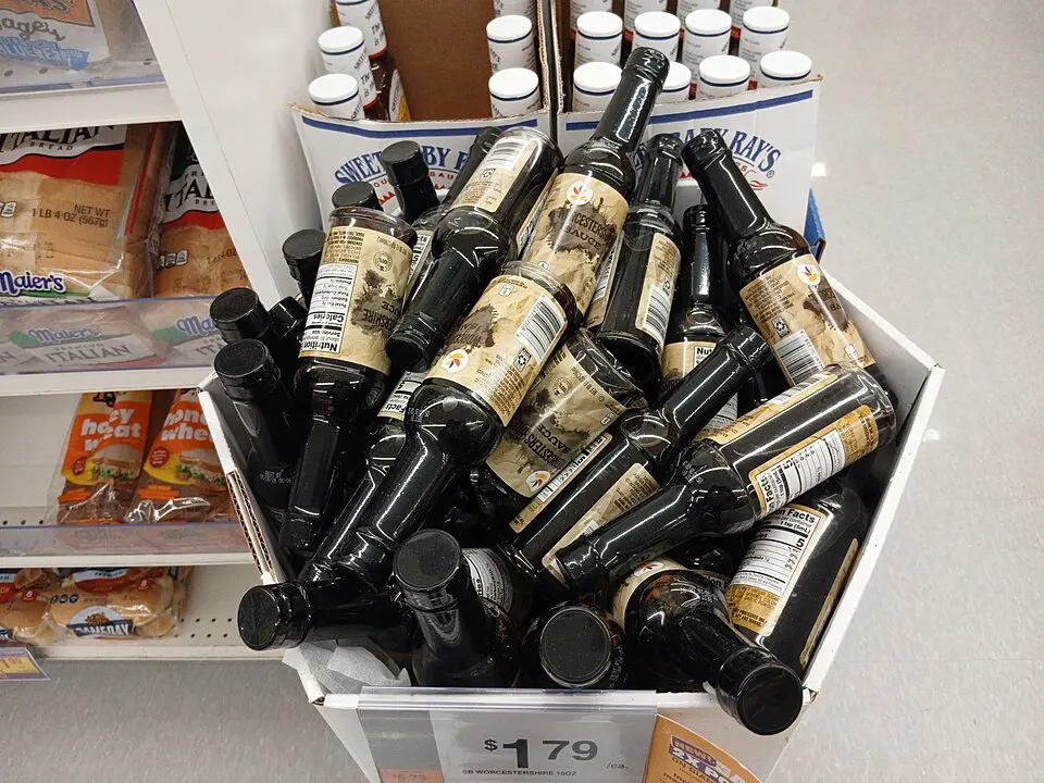 Rows of dark sauce bottles stacked in a shop display.