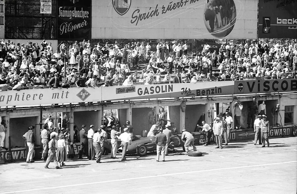 A pit crew swarming a racing car changing its wheels.