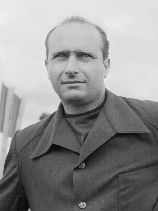 A vintage portrait of a smiling driver in a racing jacket.