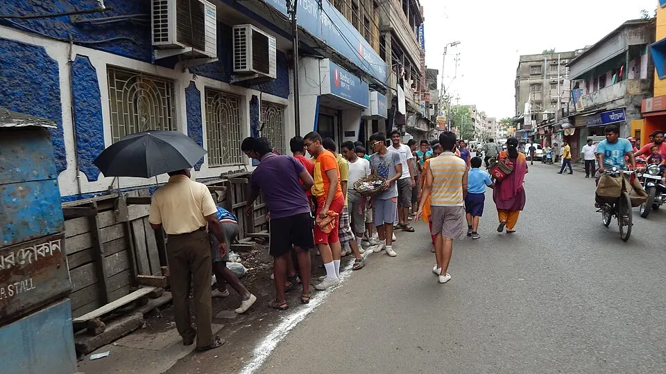 A group of young people collecting rubbish from the side of a busy street.