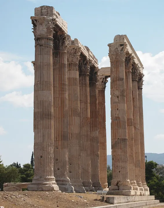 Tall fluted ancient columns with ornate capitals standing against a blue sky.
