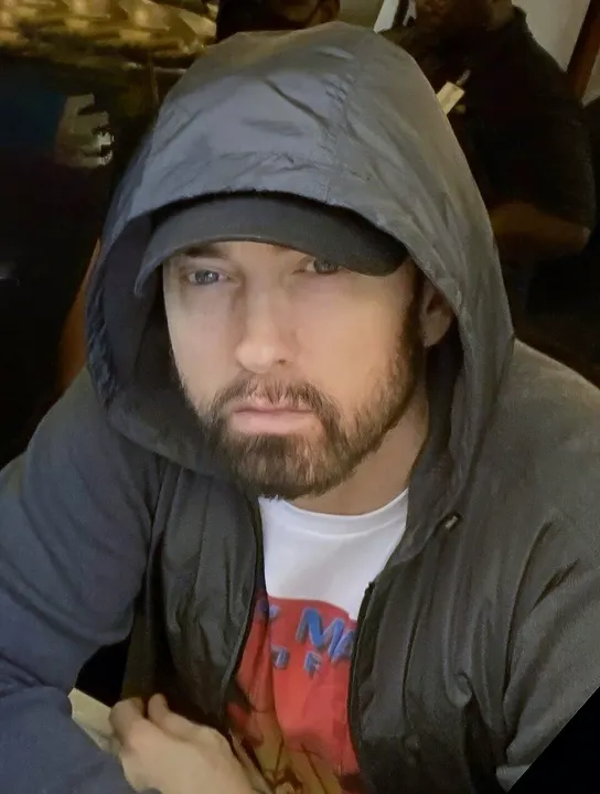 A man in a hooded top rapping into a microphone.