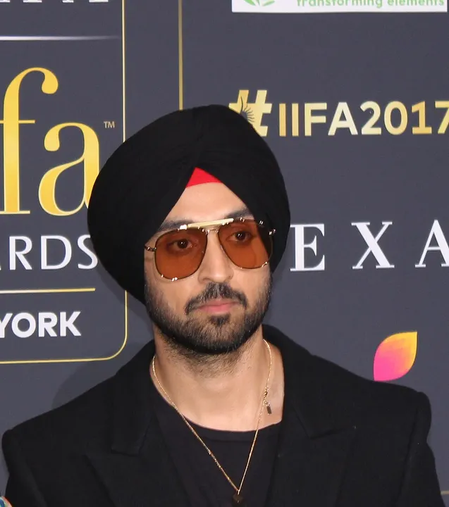 A man in a turban and bright outfit at an event.