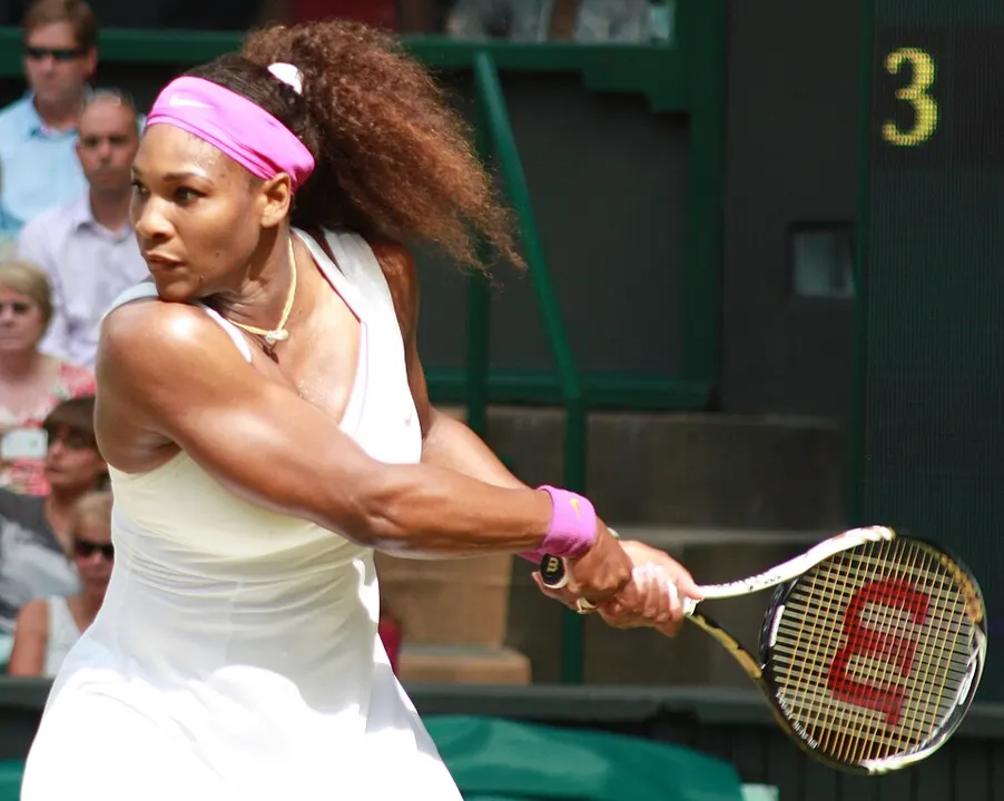 A tennis player in a white outfit holding a racket on court.