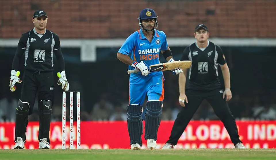 A bearded cricketer in blue Indian team kit.