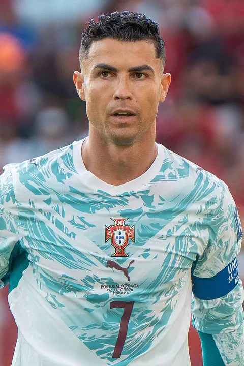 A muscular footballer in a white and green patterned kit.