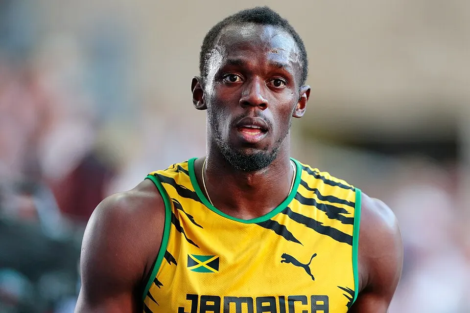 A sprinter in a yellow and green vest on the track.