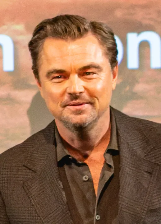 A man with swept-back light hair in a dark suit at a premiere.