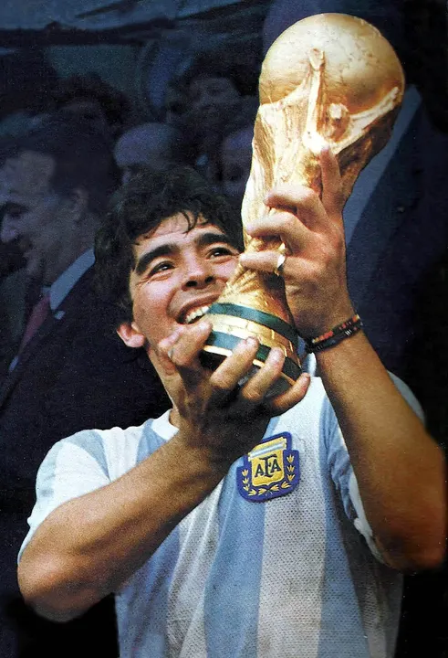 A stocky footballer with dark curly hair in a light-blue and white kit.