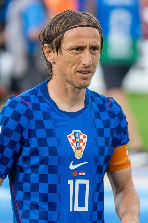 A dark-haired midfielder in a red-and-white chequered kit.