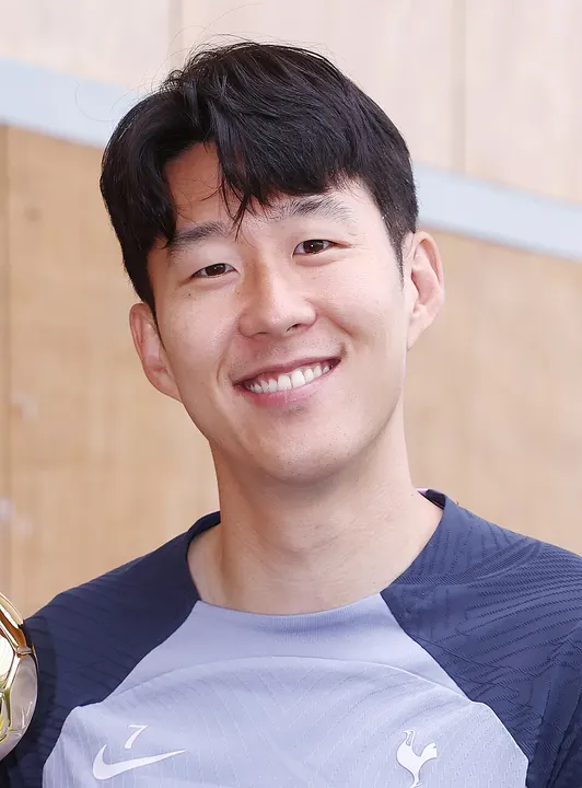 A smiling Asian footballer in a white club kit.