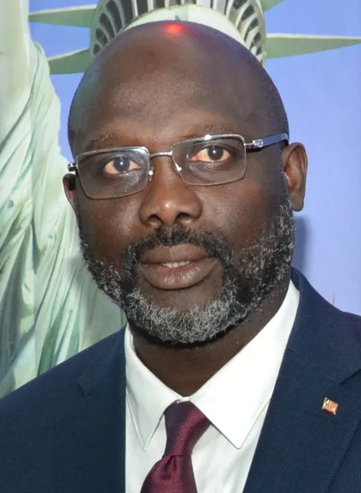 A smiling man in a suit and tie at an official event.