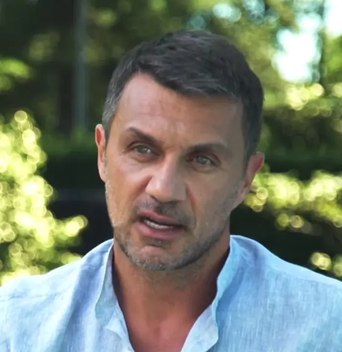 A dark-haired man in a light-blue shirt outdoors.