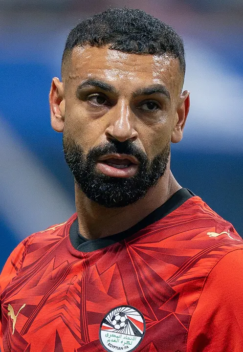 A bearded footballer with dark curly hair in a red kit.