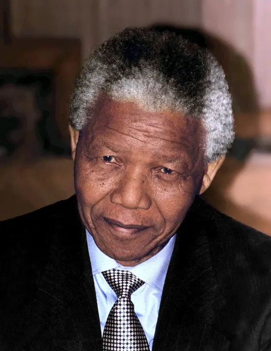 A smiling elderly man with short grey hair in a patterned shirt.