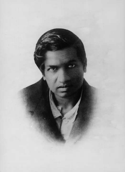 A formal portrait of a young man in a white shirt and dark cap.