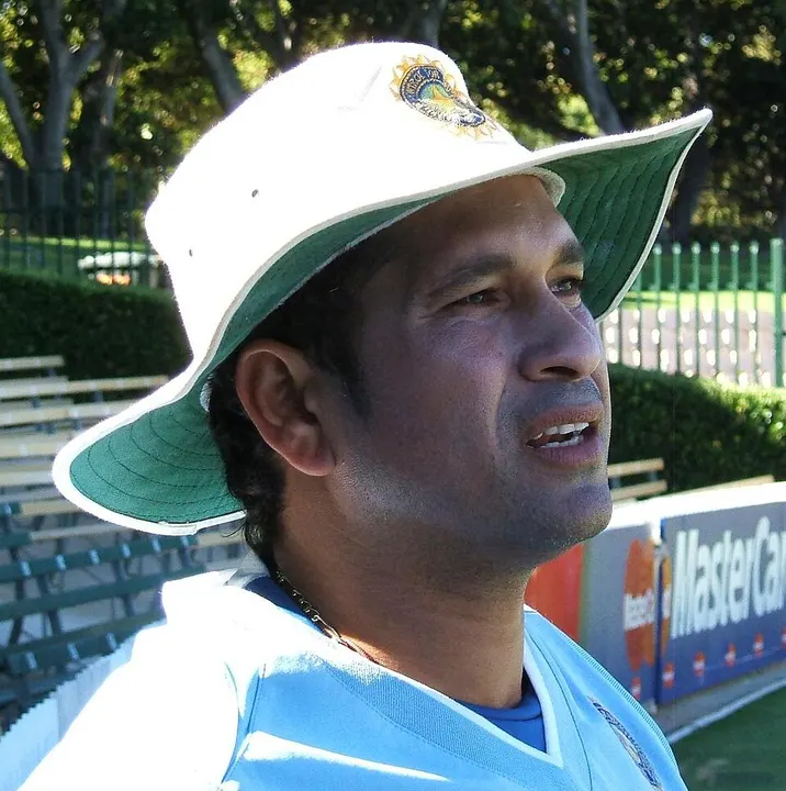 A smiling cricketer in a white sun hat and light-blue kit.