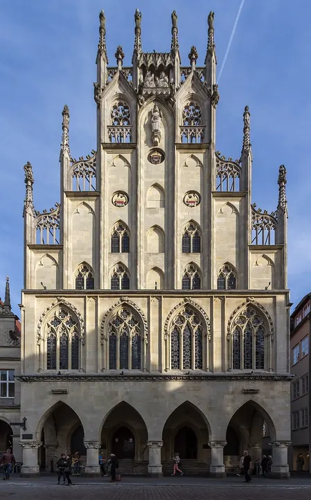 A tall Gothic stone town hall with pointed arches, spires and a decorated gable.