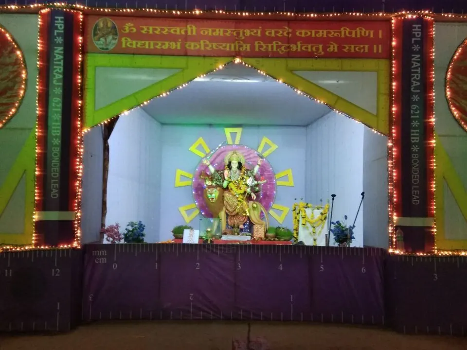 A lit-up festival stage with a decorated goddess idol riding a lion, framed by strings of lights.
