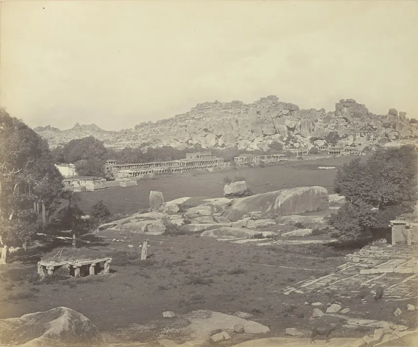 1868 की पुरानी श्वेत-श्याम तस्वीर: विशाल चट्टानों की पहाड़ी के सामने खंडहर हो चुके मंडपों की लंबी कतार।