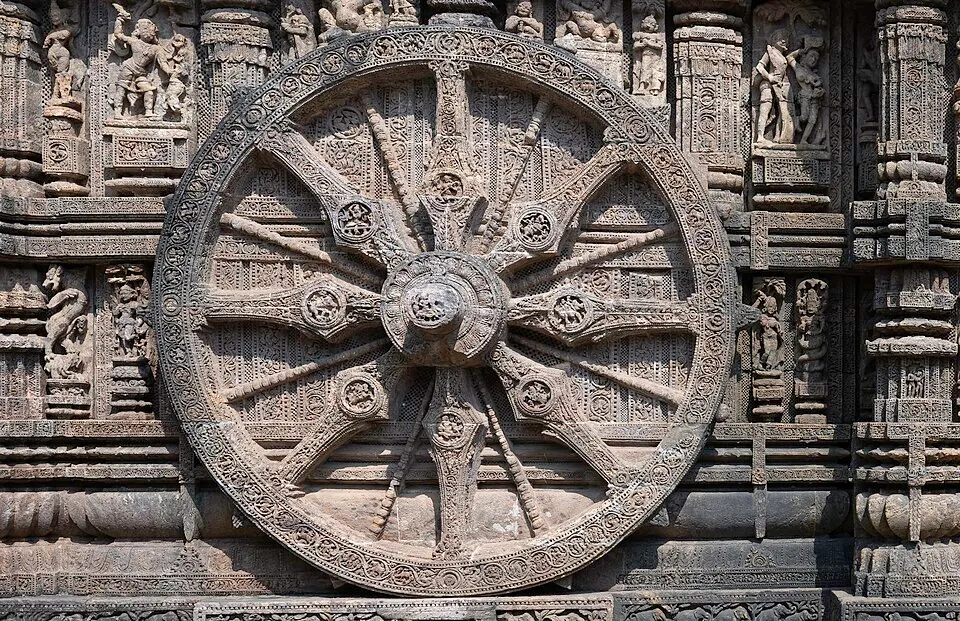 A huge carved stone chariot wheel with twelve ornate spokes set into the wall of an ancient sandstone temple.