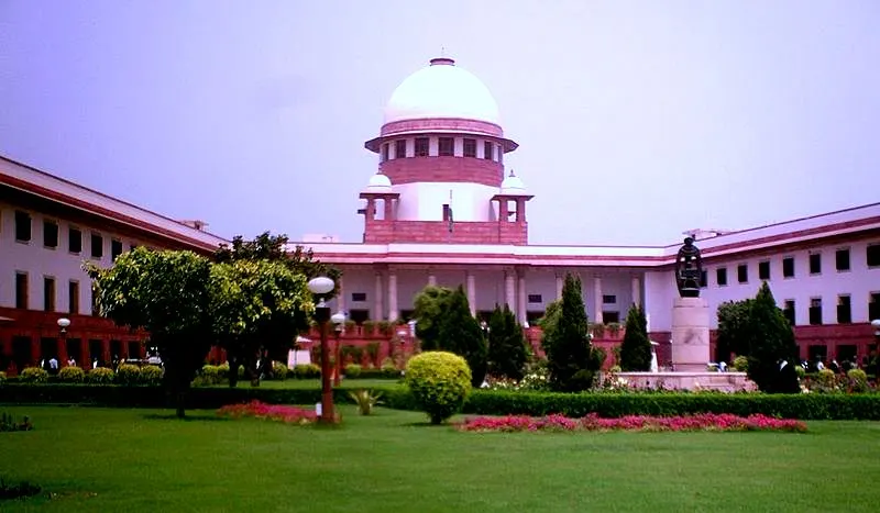 A white-domed court building with red-trimmed wings behind a green lawn and flower beds.