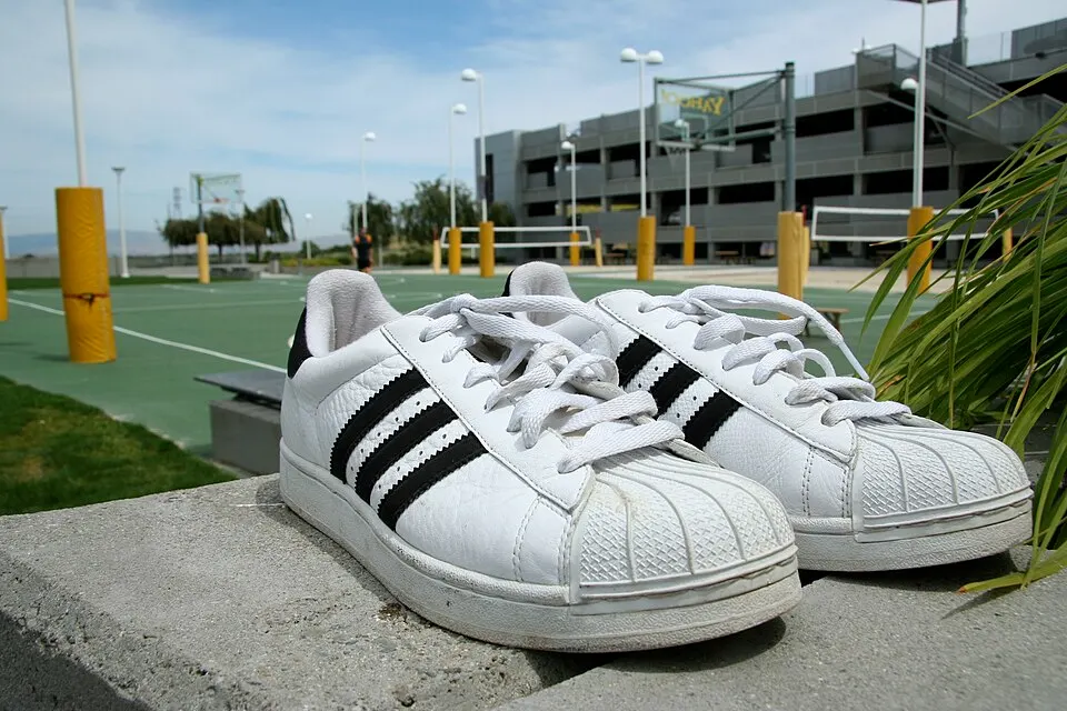 A pair of white trainers with three stripes on the side.