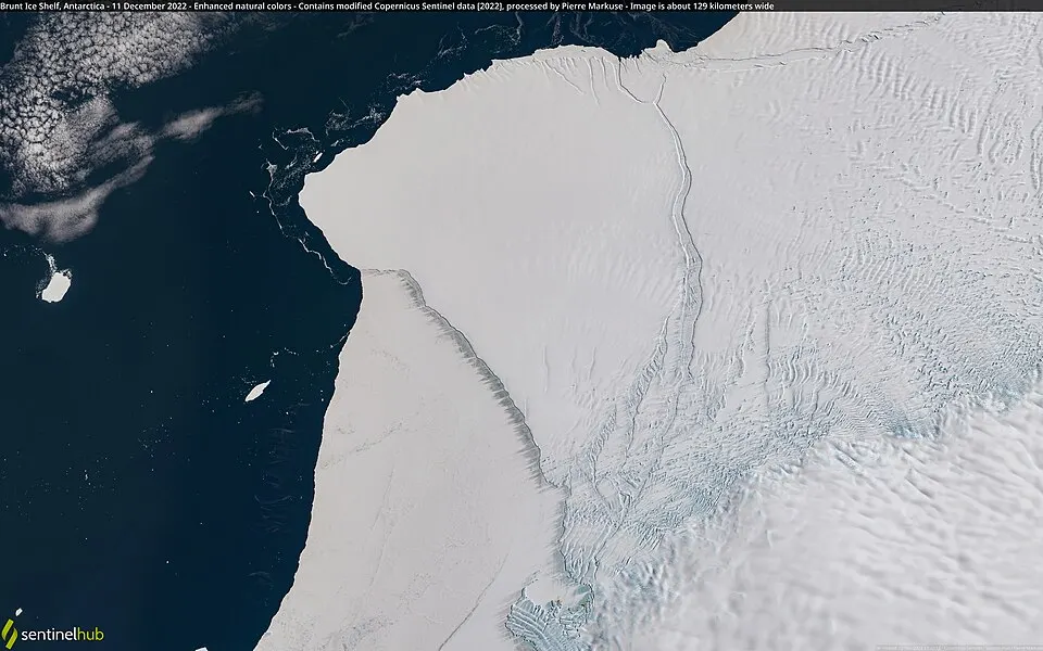 A satellite view of a vast white ice sheet meeting dark sea.