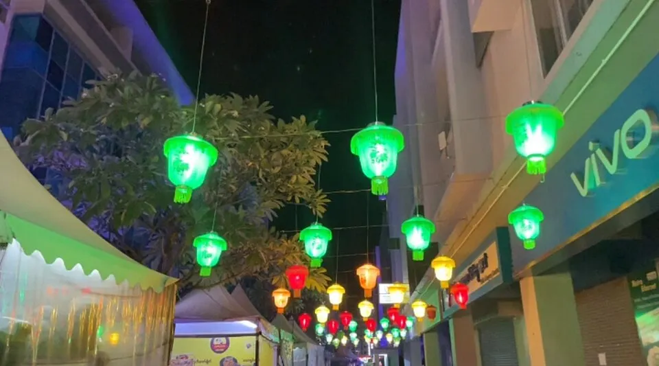 Green, red and yellow lanterns hanging on wires above a night-time street.