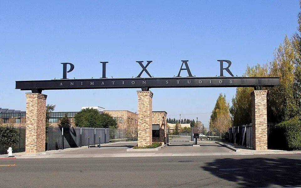 A black steel archway on brick pillars over a studio entrance gate, with large letters spelling a name on top.