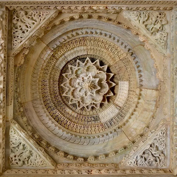 A white marble ceiling carved into concentric rings with a lotus-like pendant at the centre.